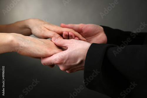 Photo: Priest holding woman hands, on black background Priest holding woman hands, on black background