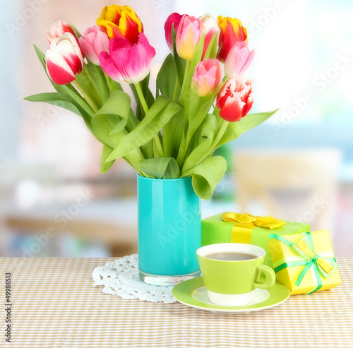 Photo: Beautiful tulips in bucket with gifts and cup of tea Beautiful tulips in bucket with gifts and cup of tea