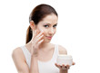 Woman applying lifting cream from container on face