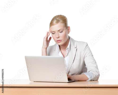Photo: Tired young businesswoman sitting at a table with laptop Tired young businesswoman sitting at a table with laptop