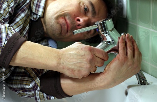 Photo: Mann installiert Wasserhahn an Waschbecken Mann installiert Wasserhahn an Waschbecken