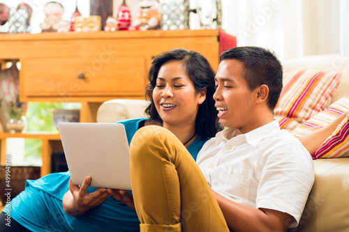 Photo: Asian people sitting in front of a notebook laughing Asian people sitting in front of a notebook laughing