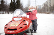 Children are riding on snowmobiles.