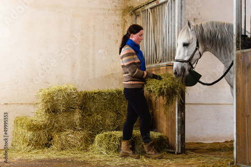 Photo: Woman give a hay for a horse Woman give a hay for a horse