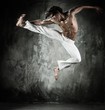 Young b-boy man with naked torso performing jumps