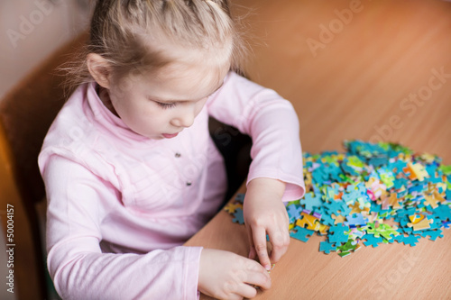 Photo: Cute little girl solving puzzles Cute little girl solving puzzles
