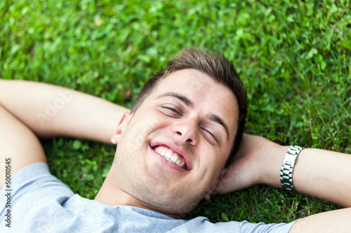 Photo: Man laying on the grass with hands behind head Man laying on the grass with hands behind head