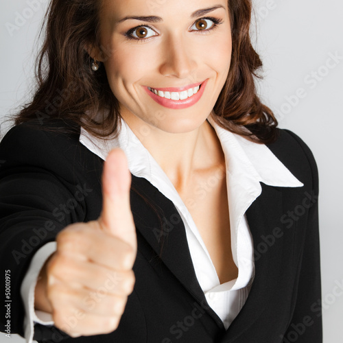 Photo: Businesswoman with thumbs up, over gray Businesswoman with thumbs up, over gray
