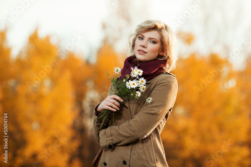 Photo: Young woman with a flowers in autumn field Young woman with a flowers in autumn field