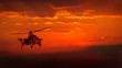Military helicopter in flight against a dramatic red sky