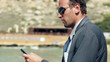 Businessman with cellphone standing on the beach, slow motion sh
