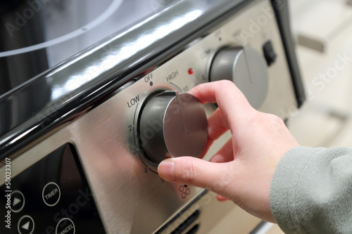 Photo: Woman turning on the oven Woman turning on the oven