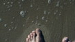 Mans foot walking on the beach, high eagle, slow motion shot at 