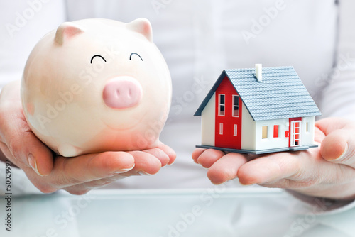 Photo: Hands holding a piggy bank and a house model Hands holding a piggy bank and a house model