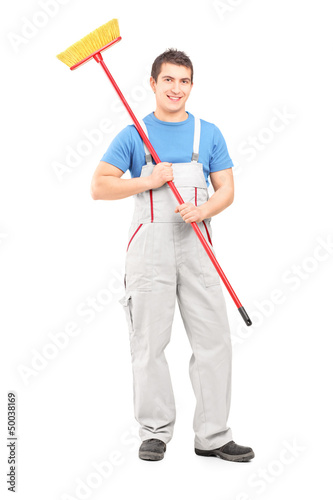 Photo: Full length portrait of a smiling cleaner in a uniform with a br Full length portrait of a smiling cleaner in a uniform with a br