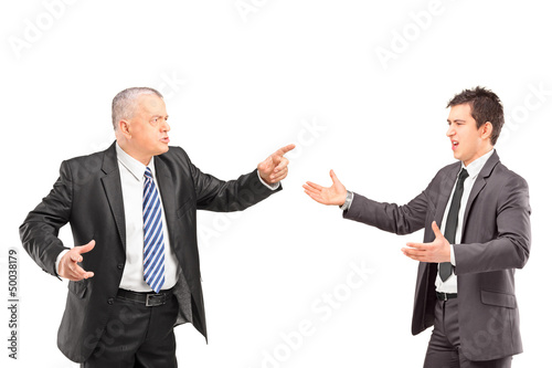 Photo: Mature man in a suit having a dispute with a young man in formal Mature man in a suit having a dispute with a young man in formal
