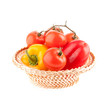 tomatoes and peppers in a wicker basket on a white background