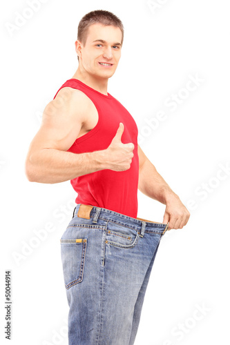 Photo: Satisfied weight loss man in a pair of old jeans giving a thumb Satisfied weight loss man in a pair of old jeans giving a thumb