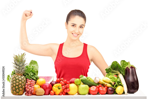 Photo: Smiling young female showing her muscle and sitting behind a pil Smiling young female showing her muscle and sitting behind a pil