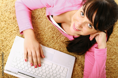 Photo: A young girl with a laptop lying on the floor A young girl with a laptop lying on the floor