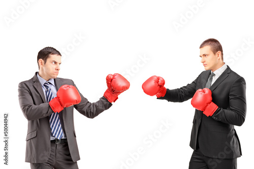 Photo: Two young businessmen with boxing gloves having a fight Two young businessmen with boxing gloves having a fight