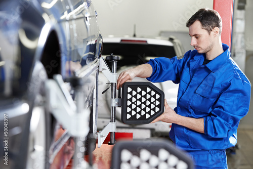 Photo: auto mechanic at wheel alignment work with sensor auto mechanic at wheel alignment work with sensor