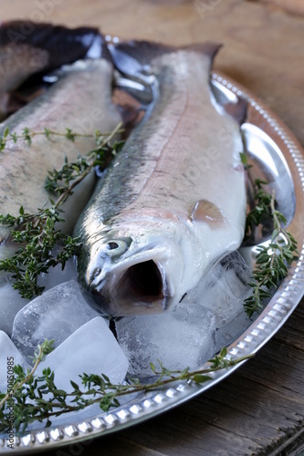 Photo: fresh raw fish trout on ice with lemon and thyme fresh raw fish trout on ice with lemon and thyme