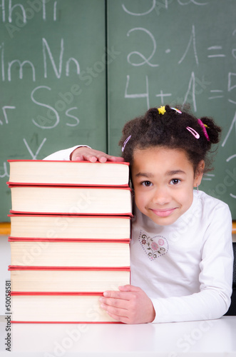 Photo: mädchen schaut hinter bücherstapel hervor mädchen schaut hinter bücherstapel hervor