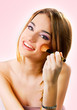 Beautiful young woman putting on makeup over a pink background