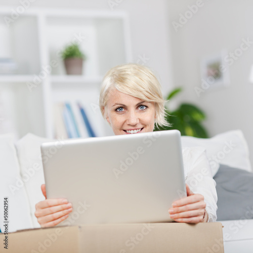 Photo: junge frau stellt laptop auf umzugskarton junge frau stellt laptop auf umzugskarton