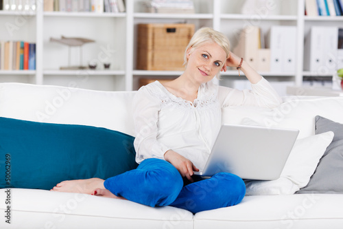 Photo: entspannte frau sitzt mit laptop auf dem sofa entspannte frau sitzt mit laptop auf dem sofa