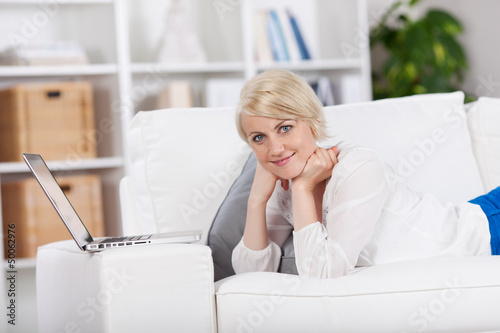 Photo: frau liegt mit ihrem laptop auf dem sofa frau liegt mit ihrem laptop auf dem sofa