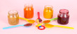 Baby puree in spoons with nipple on pink background