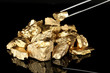 Tweezers holding golden nugget isolated on black