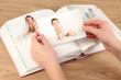 Photos in hands and photo album on wooden table
