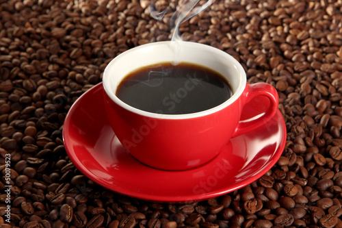 Photo: Cup of coffee on coffee beans background Cup of coffee on coffee beans background