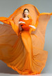 beautiful woman in long orange dress posing in the studio