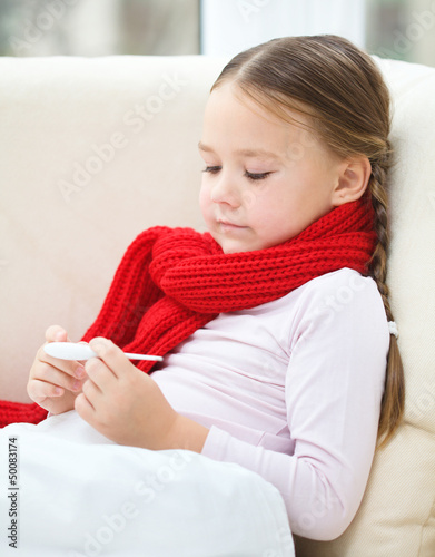 Photo: Ill little girl is reading thermometer Ill little girl is reading thermometer