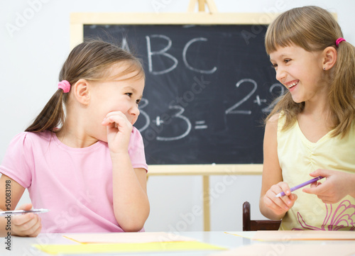 Photo: Little girls are writing using a pen Little girls are writing using a pen
