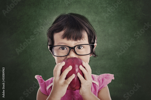 Photo: Female preschooler eats red apple Female preschooler eats red apple