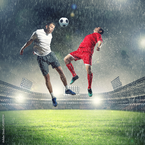 Photo: two football players striking the ball two football players striking the ball