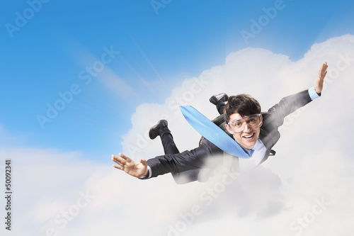 Photo: Young businessman flying with parachute on back Young businessman flying with parachute on back