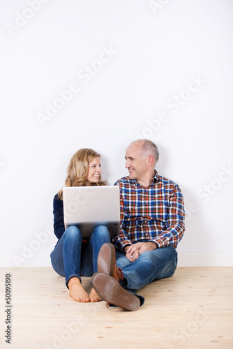 Photo: paar sitzt mit laptop in einem leeren zimmer paar sitzt mit laptop in einem leeren zimmer