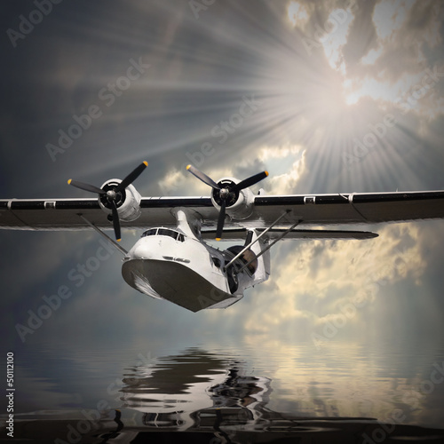 Photo: Vintage seaplane flying over a sea level. Vintage seaplane flying over a sea level.