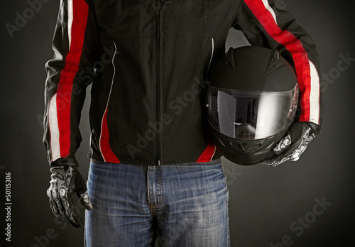 Photo: Biker with helmet in his hands. Dark background Biker with helmet in his hands. Dark background
