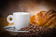 Photo: Coffee smoking on the coffee beans and croissant background Coffee smoking on the coffee beans and croissant background