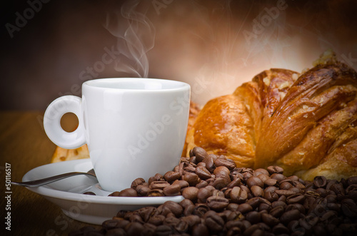 Photo: Coffee smoking on the coffee beans and croissant background Coffee smoking on the coffee beans and croissant background