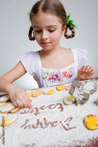 Photo: Happy Easter - lovely girl making easter cookies Happy Easter - lovely girl making easter cookies