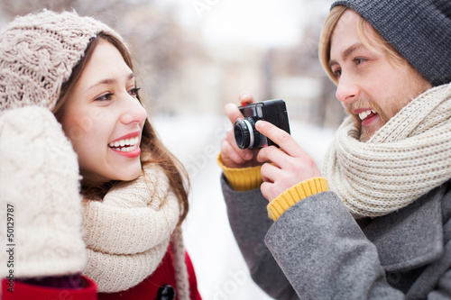 Photo: Young man taking photo of woman in winter Young man taking photo of woman in winter