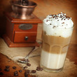 latte macchiato with cocoa powder and coffee beans on wooden tab